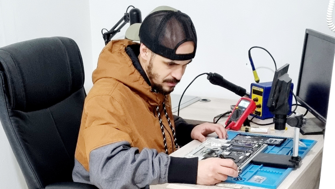 Técnico de RepairME reparando la placa madre de un notebook en el taller